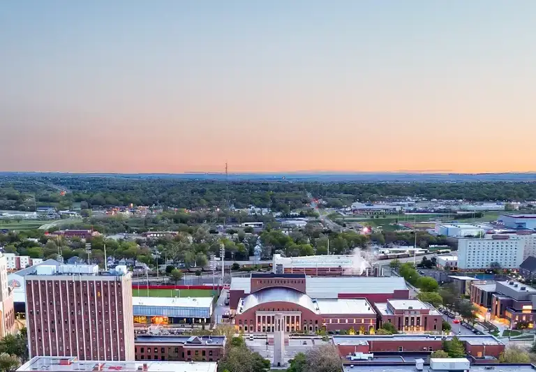Aerial view of Sioux Falls, South Dakota at sunset, showcasing the Denny Sanford PREMIER Center and surrounding cityscape.